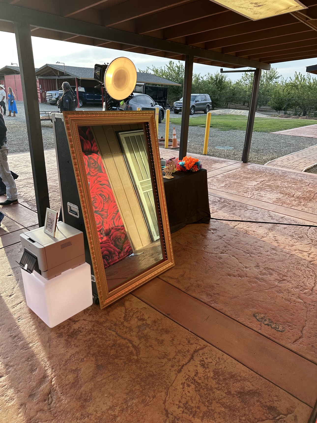 Golden-framed mirror photobooth set up beside a red rose backdrop