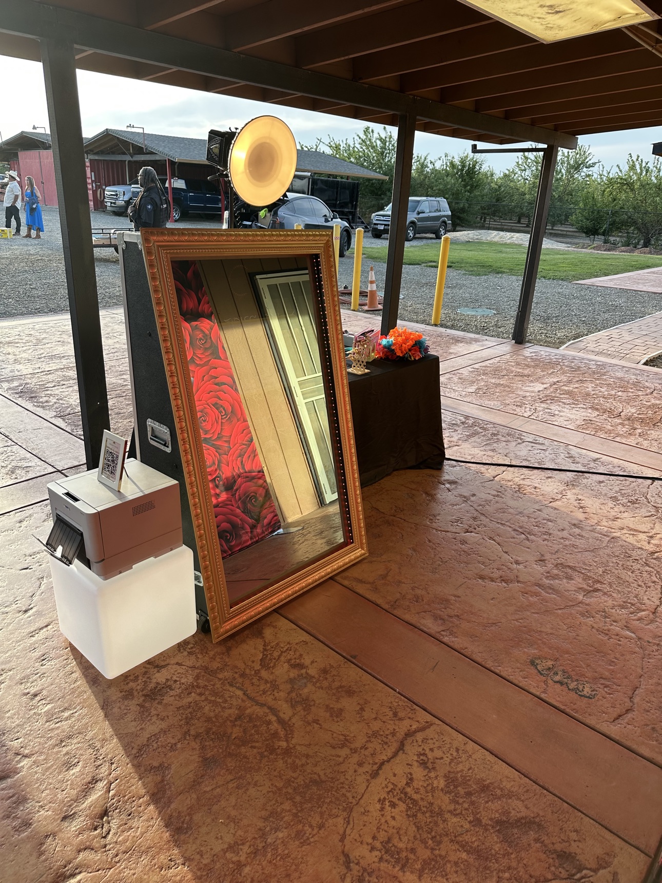 Mirror photo booth under an outdoor pavilion with a red rose backdrop